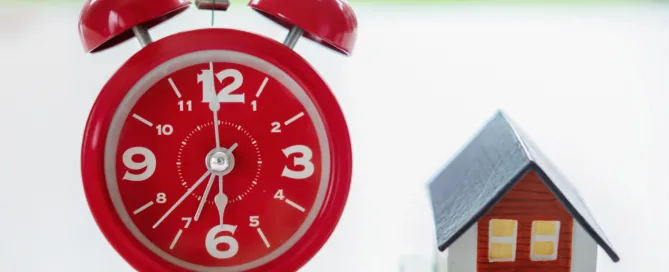 Red Clock Next To House Model