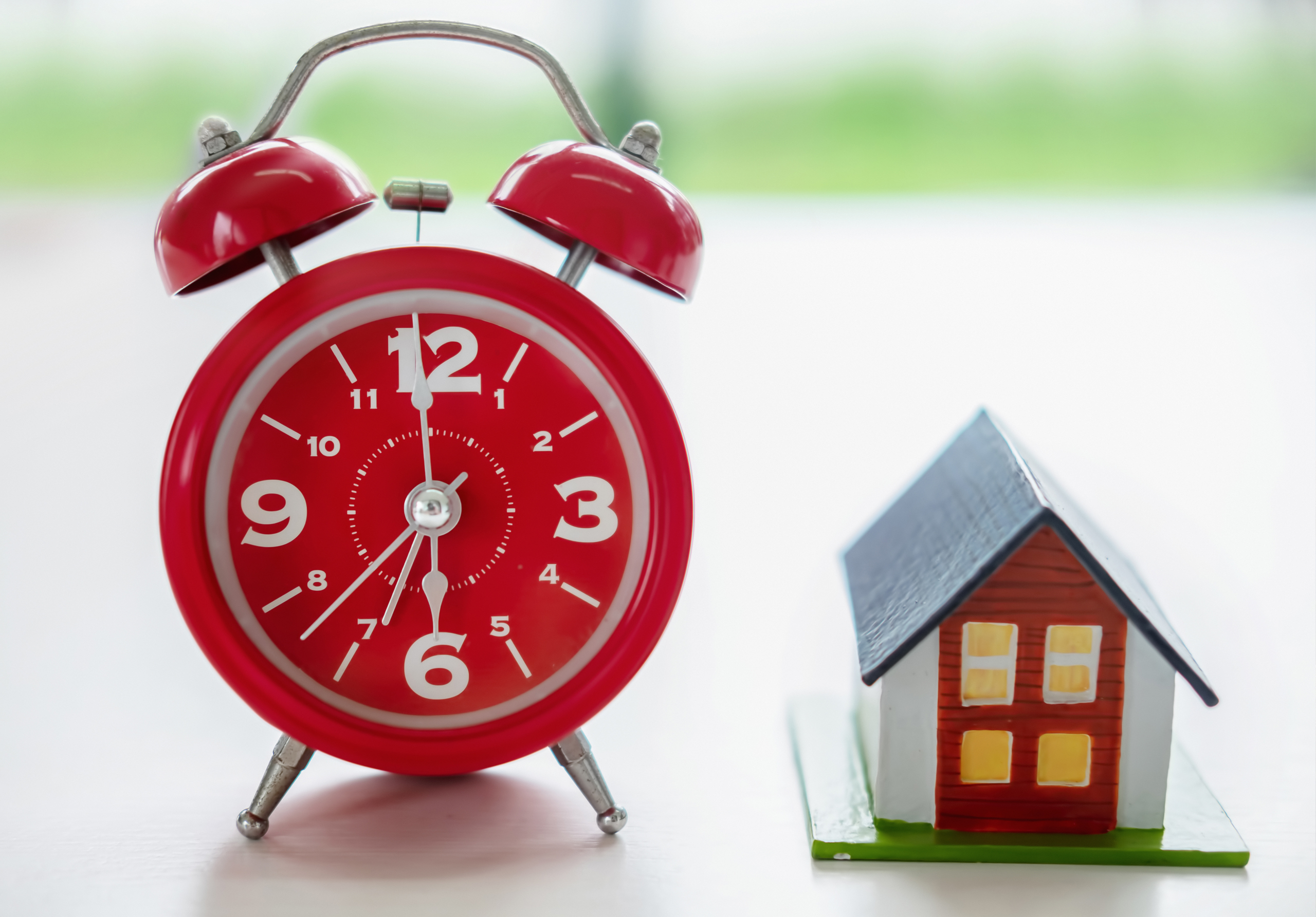 Red clock next to house model